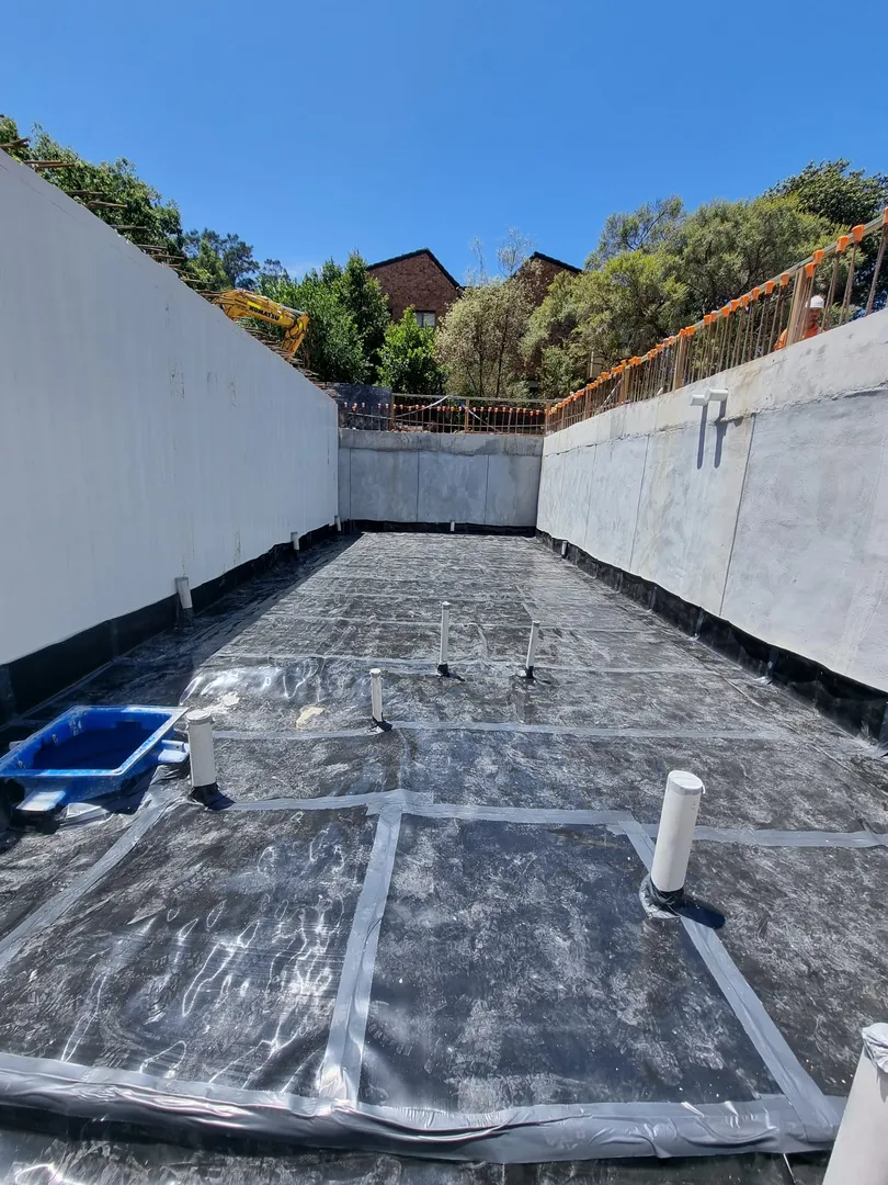 Waterproofed basement under construction with blue sky.