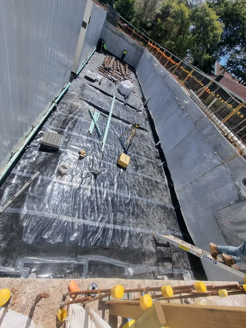 Construction site workers installing waterproofing membrane.
