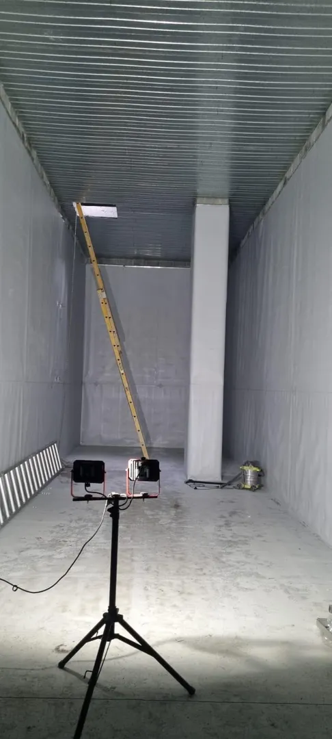 Construction ladder and lights in steel-walled space.