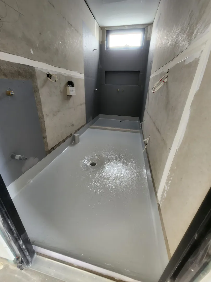 Bathroom under construction with window and plumbing.